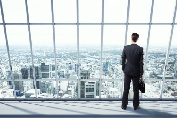 Businessman standing in front of large window looking over big city