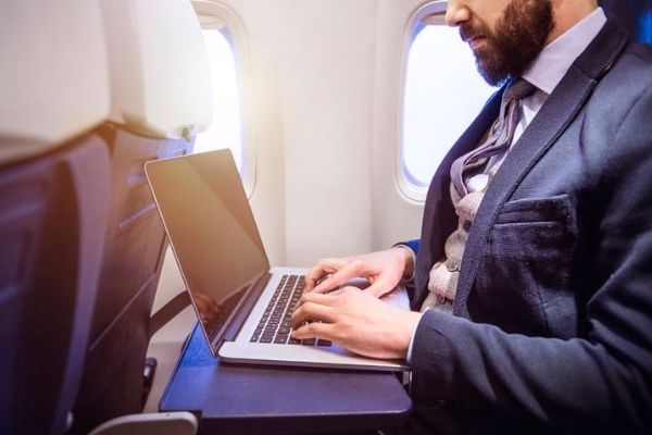 A person sitting on a plane working on their laptop