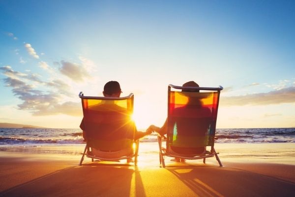 Two seniors in deck chairs on the beach.