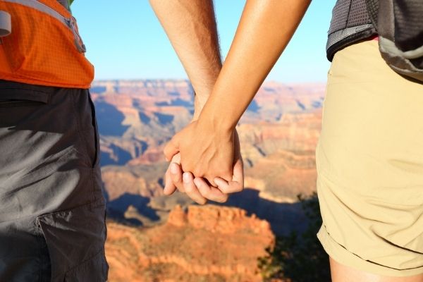 Two people holding hands in front of Grand Canyon in USA