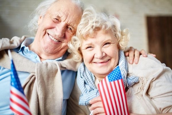 Senior couple with US flags smiling at camera