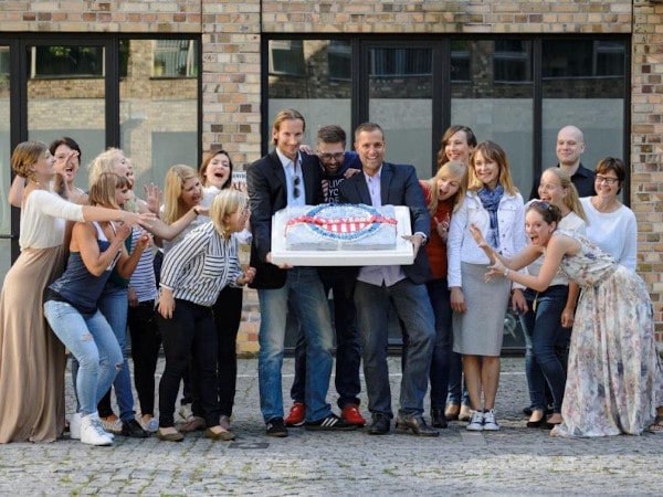 The team from The American Dream gathered around a large cake.