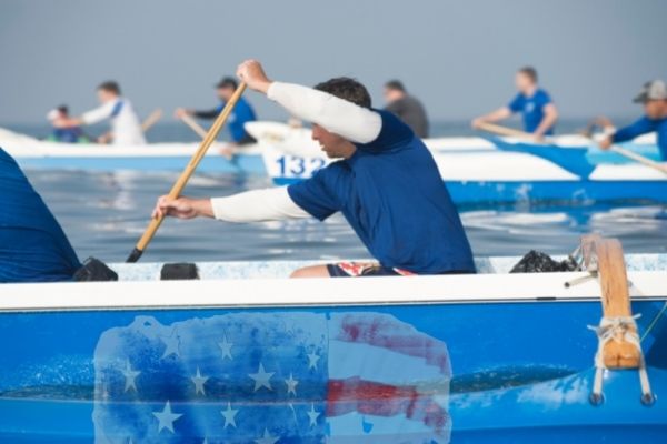 Several people paddle blue boats in competition