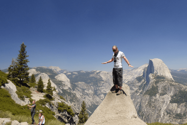 A USA tourist stands on a rocky ledge at a canyon