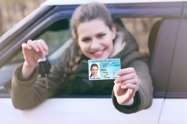 Woman with key and driver's license sitting in a car